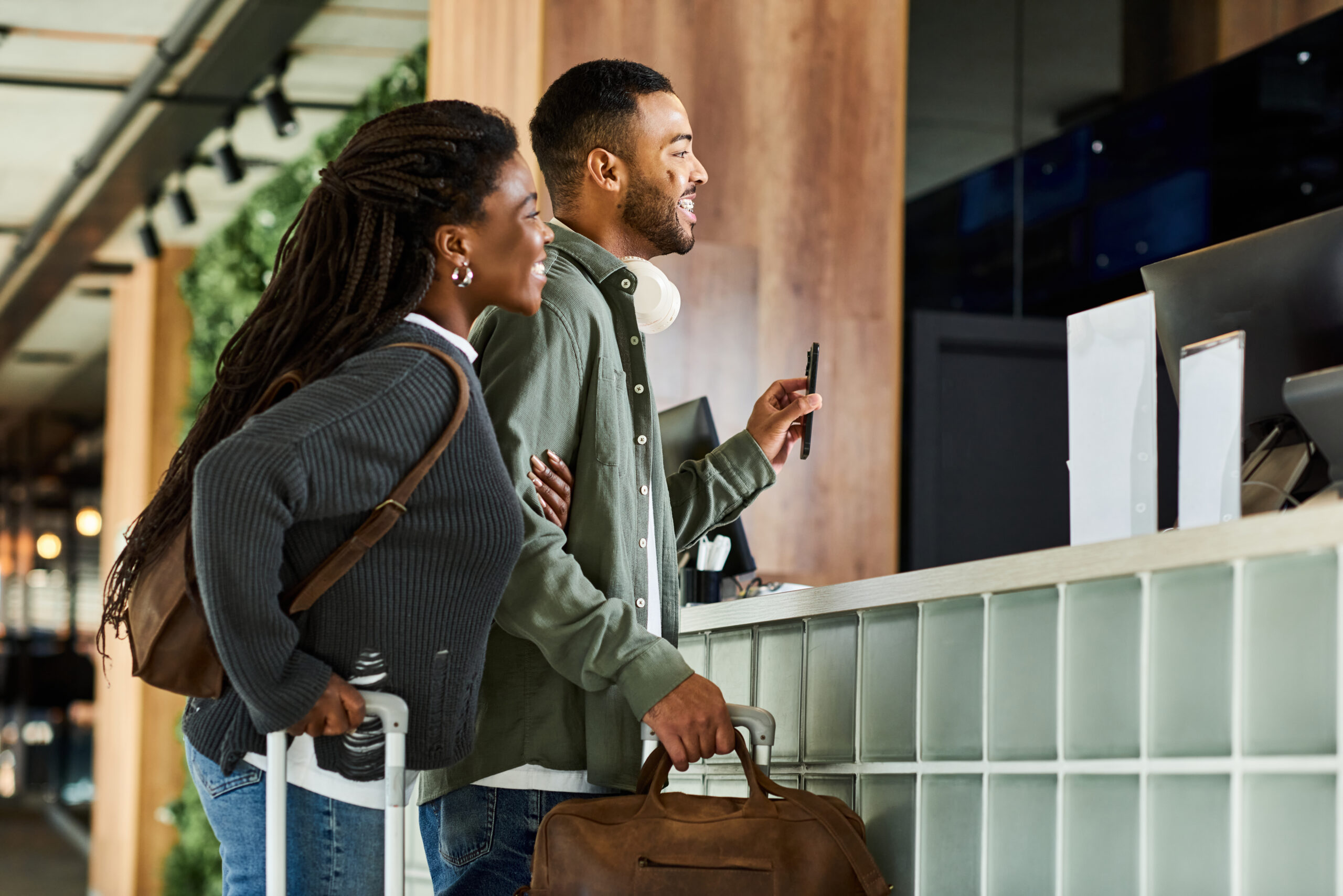 A cheerful couple smiles as they check in at the hotel lobby, ready to embark on their vacation adventure.